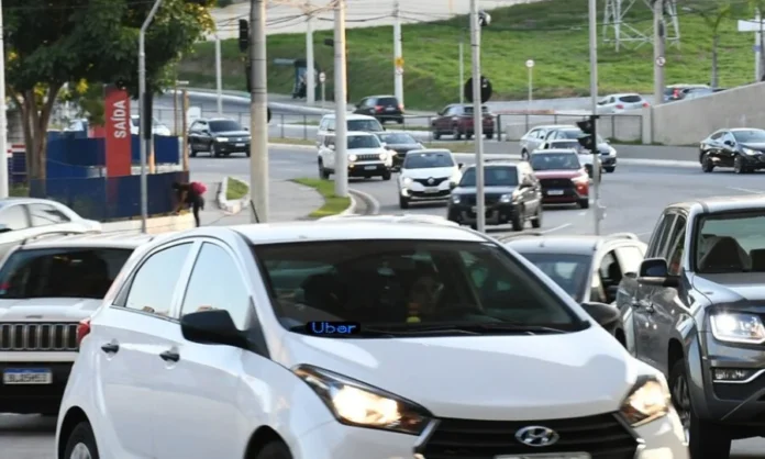 Santa Catarina propõe isenção de IPVA para motoristas de app Carro branco em trânsito urbano com letreiro de LED azul escrito Uber no para-brisa, representando motoristas de aplicativos que podem receber isenção de IPVA em Santa Catarina através de projeto na Alesc.