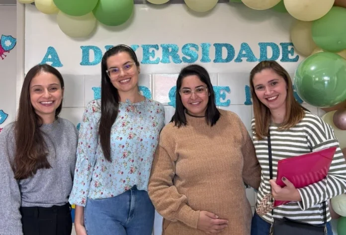 São João do Sul realiza Dia D de saúde para mães atípicas Quatro mulheres sorridentes posam juntas durante o Dia D de saúde para mães atípicas em São João do Sul. Ao fundo, decoração com balões verdes e azuis e parte de um painel sobre diversidade.