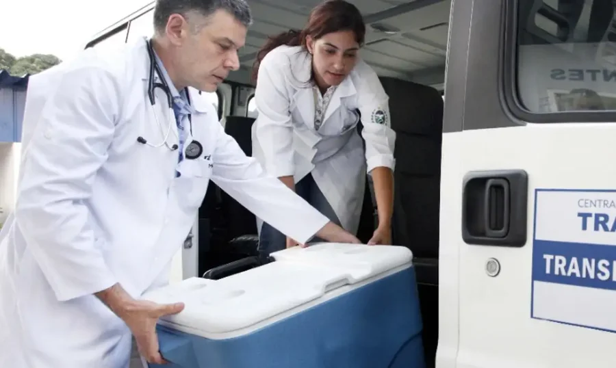 Profissionais de saúde transportam caixa térmica para transplante de órgãos durante operação de logística médica