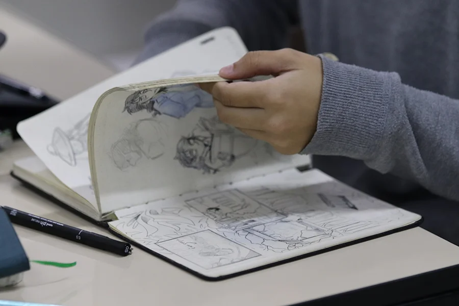Estudante folheia caderno de desenhos em curso de Artes Visuais da Unesc, destaque no Enade das licenciaturas 2025.
