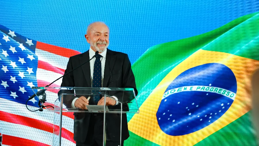 Presidente em evento oficial com bandeiras do Brasil e dos Estados Unidos ao fundo, em matéria sobre gastos com viagens do governo federal em 2025.