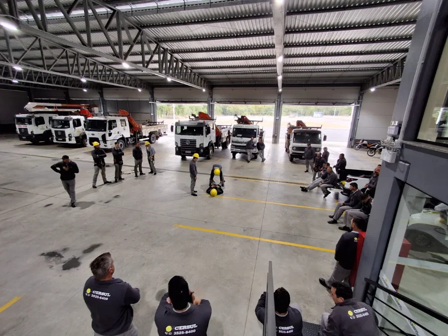 Trabalhadores da CERSUL participam de capacitação para operação de guindaste e cesta aérea em garagem com veículos da cooperativa.