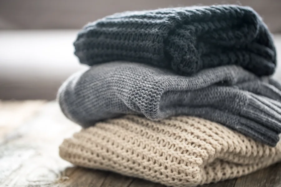 Roupas de inverno dobradas representam a Campanha do Agasalho em Nova Veneza, que arrecada doações para famílias em vulnerabilidade social.