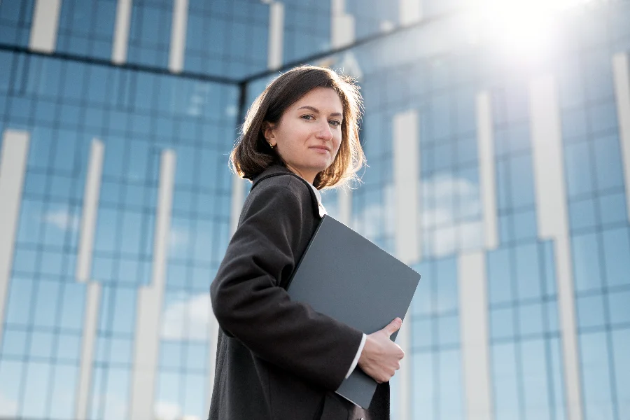Carreira em T ganha força com avanço da tecnologia Profissional com notebook em frente a prédio corporativo representa carreira em T, tecnologia e perfil multidisciplinar no mercado de trabalho.