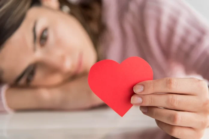 Dia dos Namorados acende alerta emocional em solteiros Mulher segurando coração vermelho em imagem ilustrativa sobre Dia dos Namorados, solteiros e saúde emocional