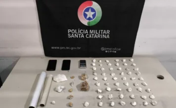 Homem é preso com cocaína e crack em Sombrio Drogas apreendidas pela Polícia Militar em Sombrio, com porções de cocaína e crack, balança de precisão e celulares sobre mesa.