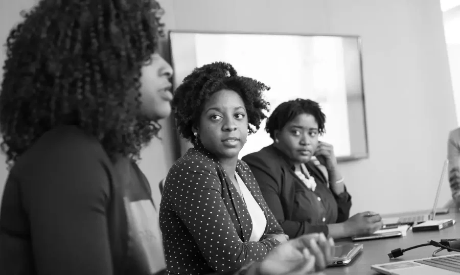 Jovens mulheres negras em reunião profissional, tema relacionado à desigualdade racial, desemprego e mercado de trabalho no Brasil
