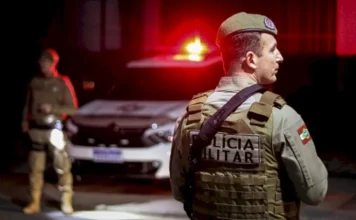 PMSC cumpre 1.445 mandados em operação no estado Policial militar da PMSC em operação noturna com viatura ao fundo durante cumprimento de mandados em Santa Catarina