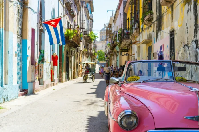 Venezuela, Irã, Cuba e Coreia do Norte lideram inflação Rua de Havana, em Cuba, com bandeira cubana e carro antigo, em contexto sobre inflação alta, crise econômica e perda de poder de compra no país.