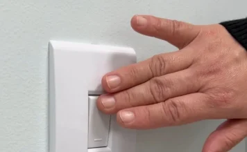 Mulher volta a ter energia após cinco anos em Criciúma Mão acionando interruptor de energia elétrica em residência de Criciúma após atuação do MPSC em caso de violência doméstica.