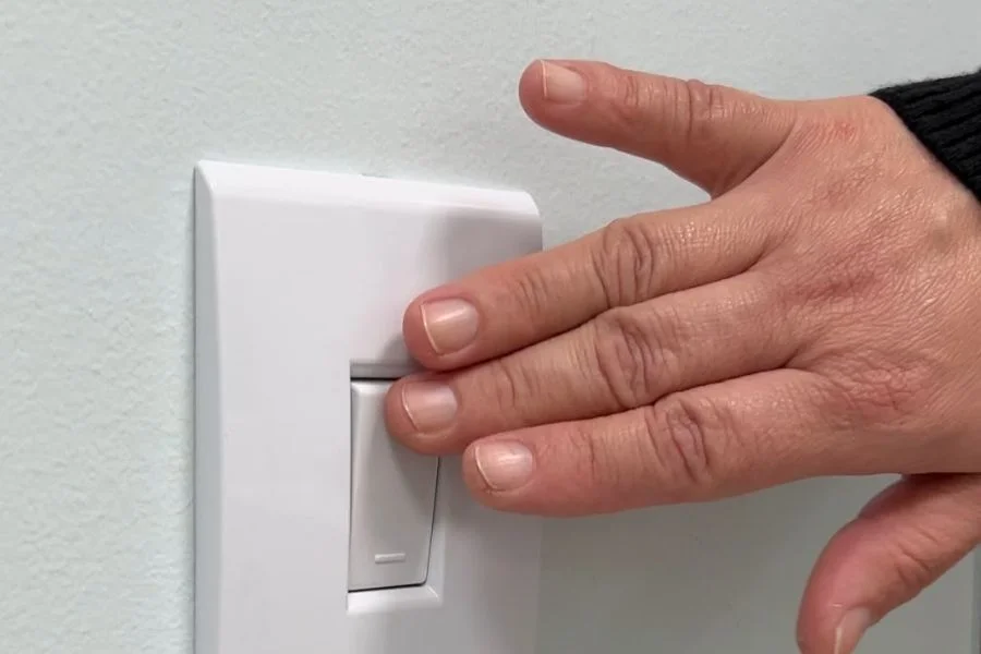 Mão acionando interruptor de energia elétrica em residência de Criciúma após atuação do MPSC em caso de violência doméstica.