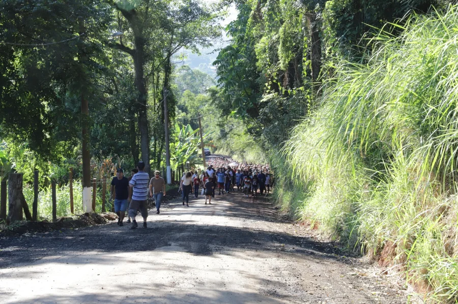 Romeiros caminham pela rua Martinho Brunelli, no bairro Mina União, em Criciúma, via de acesso ao Morro da Cruz que receberá pavimentação asfáltica.