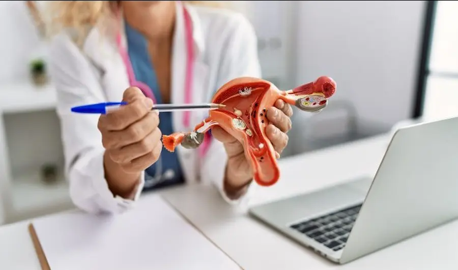 middle-age-blonde-woman-wearing-doctor-uniform-holding-anatomical-model-of-uterus-at-clinic-761x450