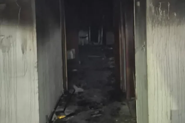 Corredor com paredes e materiais atingidos por inc&ecirc;ndio em galp&atilde;o abandonado em Crici&uacute;ma.