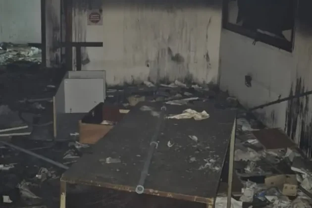 Interior de galp&atilde;o abandonado com m&oacute;veis, documentos e materiais atingidos pelo inc&ecirc;ndio em Crici&uacute;ma.