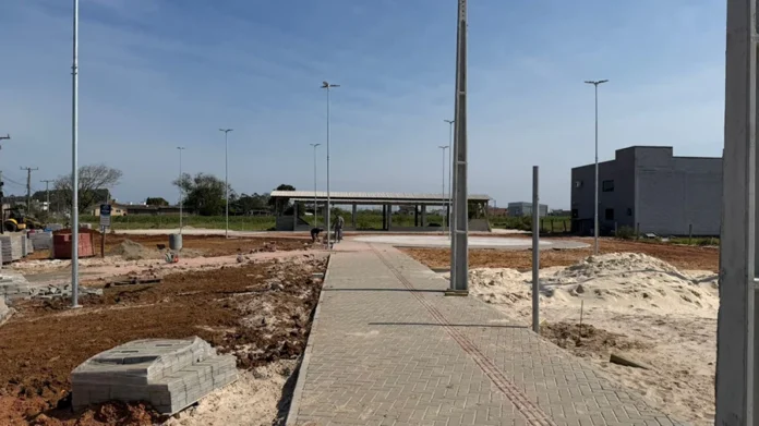Araranguá terá nova praça de 3 mil m² no Caverazinho Obras de construção da nova praça pública no bairro Caverazinho, em Araranguá, com calçamento e postes de iluminação sendo instalados.