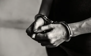 Justiça decreta prisão preventiva de suspeito em Araranguá Homem algemado em imagem ilustrativa sobre prisão preventiva de suspeito de agressão contra jovem em Araranguá.