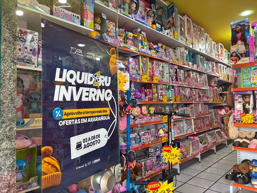 Loja participante da Liquidaru em Araranguá com cartaz da campanha e prateleiras de brinquedos em promoção.