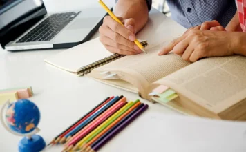 Nova Veneza avança no Ideb 2025 e fica em 2º na Amrec Estudante realiza atividade com livro, caderno e computador, ilustrando o avanço de Nova Veneza no Ideb 2025.