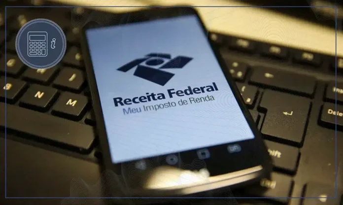 Receita abre consulta ao último lote do IRPF de 2026 Celular exibe a página Meu Imposto de Renda da Receita Federal sobre teclado de computador, em referência à consulta da restituição do IRPF 2026.