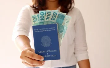 Serviços lideram geração de empregos em Santa Catarina Mulher segura carteira de trabalho e notas de real, representando a geração de empregos formais no setor de serviços em Santa Catarina.