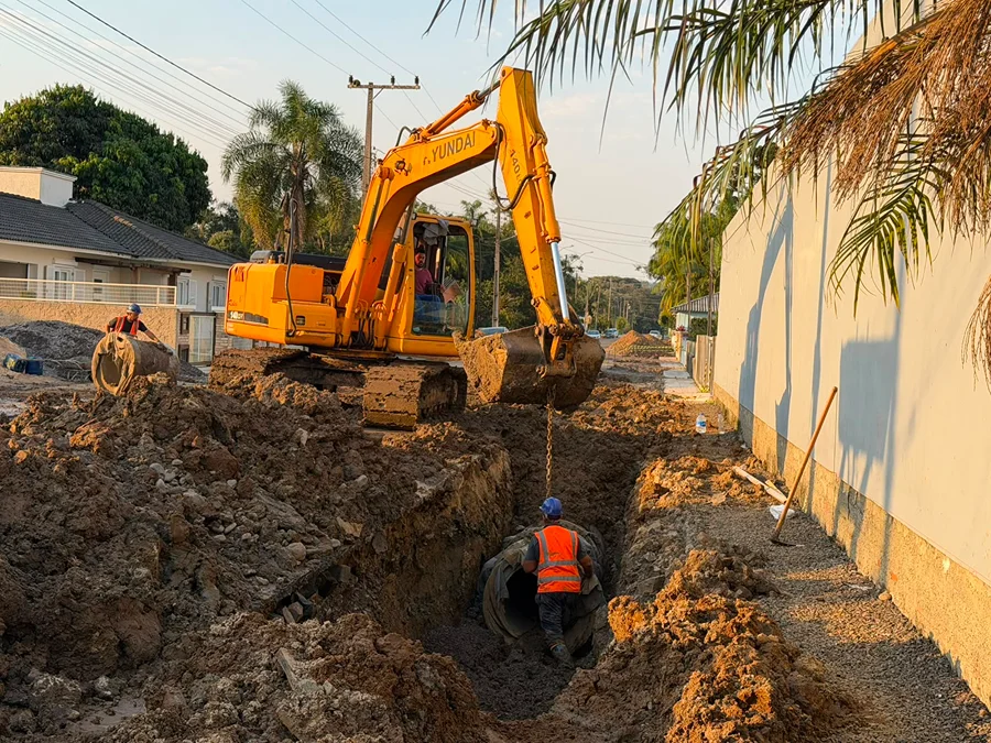 Escavadeira e trabalhadores instalam tubulação de drenagem para escoamento de águas pluviais no Centro de Turvo.