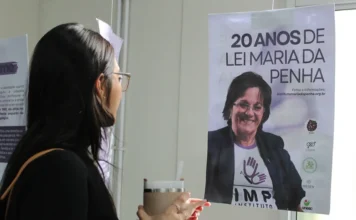Unesc promove exposição pelos 20 anos da Lei Maria da Penha Mulher observa painel da exposição sobre os 20 anos da Lei Maria da Penha na Unesc.