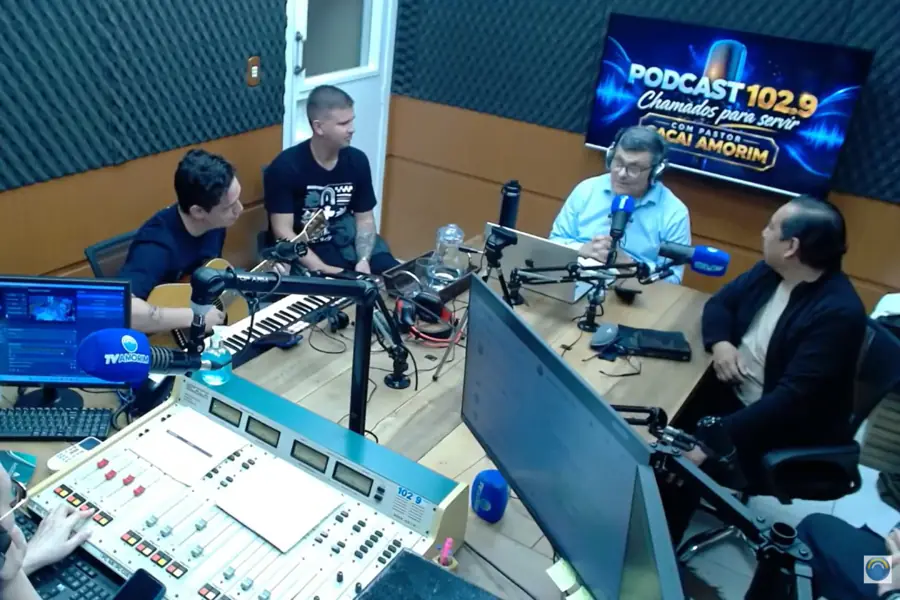 Participantes durante gravação do Podcast 102.9 “Chamados para Servir” em estúdio de rádio, com microfones e equipamentos de transmissão.