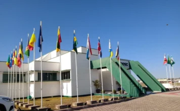 AMESC e Sebrae levam empresários à Festuris em Gramado Fachada da sede da AMESC, em Araranguá, com bandeiras dos municípios e estrutura verde na entrada.