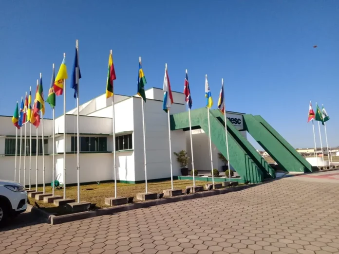 AMESC e Sebrae levam empresários à Festuris em Gramado Fachada da sede da AMESC, em Araranguá, com bandeiras dos municípios e estrutura verde na entrada.