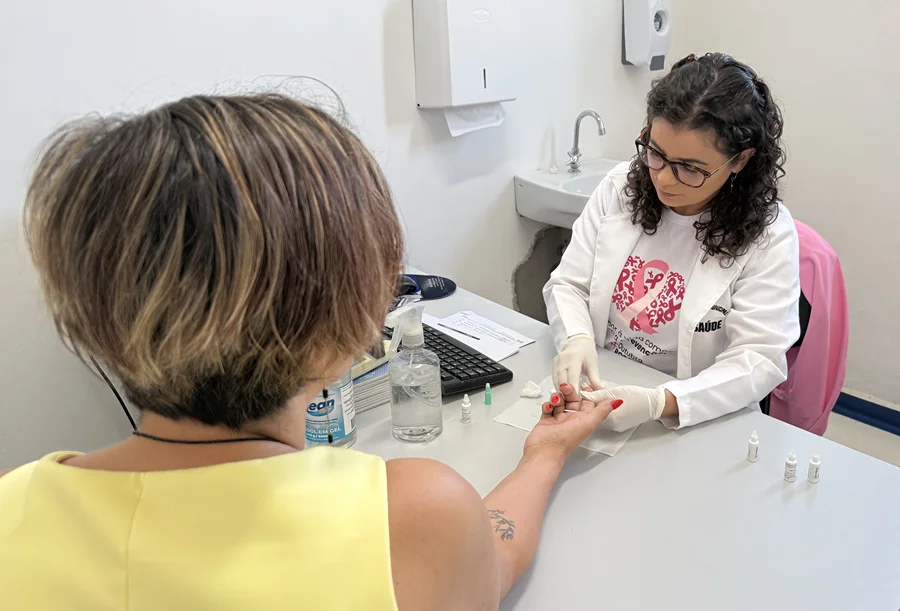 Profissional de saúde realiza teste rápido em mulher durante o Dia D do Outubro Rosa em Morro da Fumaça.