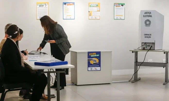 Eleitor deve deixar celular antes de entrar na cabine Eleitora entrega celular antes de acessar a cabine de votação durante as eleições de 2026.