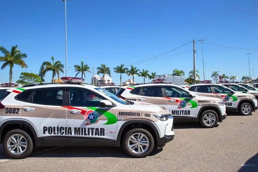 Viaturas da Polícia Militar de Santa Catarina estacionadas lado a lado em área aberta.
