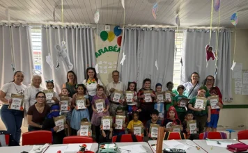 Maracajá entrega 1.530 kits educativos para Dia das Crianças Estudantes fantasiados exibem kits educativos ao lado de adultos em sala de aula de Maracajá durante comemoração do Dia das Crianças.