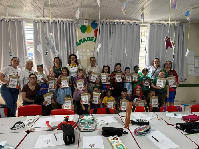 Maracajá entrega 1.530 kits educativos para Dia das Crianças Estudantes fantasiados exibem kits educativos ao lado de adultos em sala de aula de Maracajá durante comemoração do Dia das Crianças.