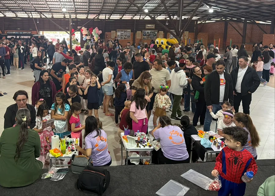 Crianças recebem pintura facial durante comemoração do Dia das Crianças no Pavilhão do Arroz, em Meleiro, acompanhadas por familiares.