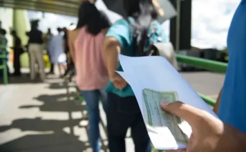 Saiba o que pode e o que é proibido no dia da eleição Eleitor segura título de eleitor e documento enquanto aguarda na fila de votação nas Eleições 2026.