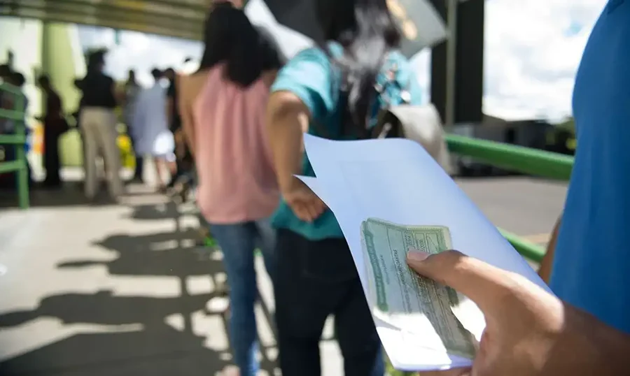 Eleitor segura título de eleitor e documento enquanto aguarda na fila de votação nas Eleições 2026.
