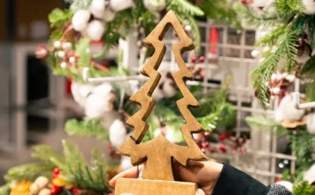 Vitrines de Natal terão R$ 7,5 mil em prêmios em Araranguá Mãos seguram árvore de Natal de madeira diante de enfeites natalinos, em imagem que ilustra o concurso de vitrines da CDL Araranguá.